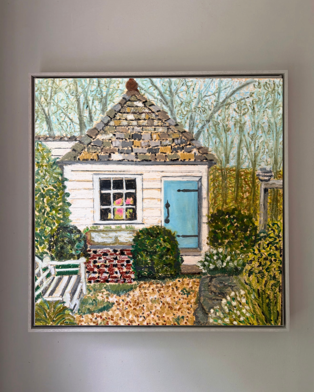 Framed artwork of a small house with a garden on a gray wall